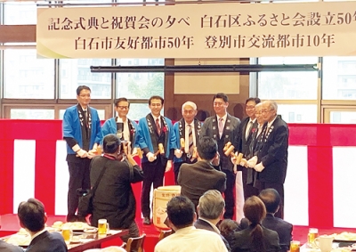 写真：節目を記念して鏡割りを行う日野会長（右端）や小笠原市長（右から３人目）（提供写真）