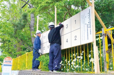 写真：選挙用ポスター掲示板の設置作業をする作業員＝２０日、地球岬団地バス停前