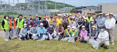 写真：集合場所のテニスコート横の駐車場で小学生から８０代の高齢者まで、和気あいあいとごみ拾いに汗を流しました