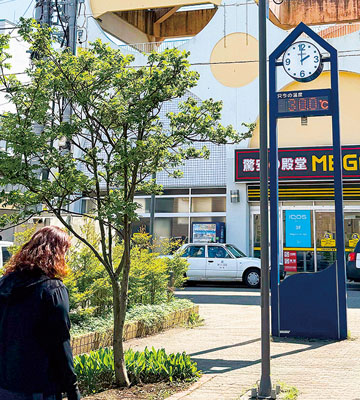 写真：室蘭市内の屋外気温計が３０度を示す中を足早に歩く市民＝２４日、午後２時ごろ