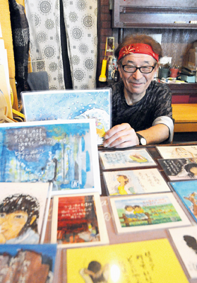 写真：詩画の作品を手に来場を呼びかける井樫さん