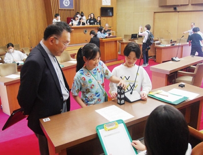 写真：安田議会事務局長の案内で議場を見学するみなと小学校の児童