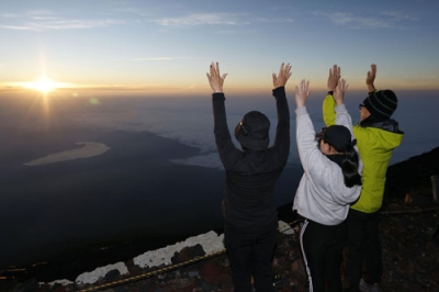 写真：山開きを迎えた富士山の山頂で、御来光に向かって万歳する登山客ら＝１日午前４時３８分