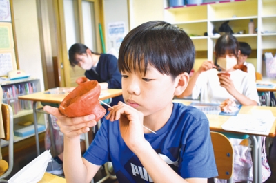 写真：竹串で土器にオリジナルの模様を付ける児童