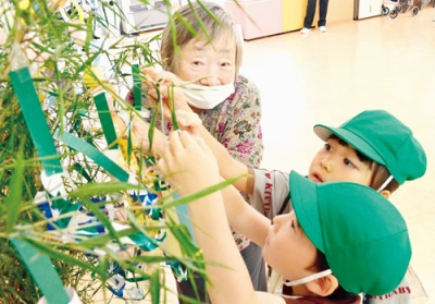 写真：ササに短冊を飾り付ける園児と入所者