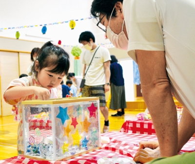 写真：水槽内の小物入れ目がけてコインを落とす園児