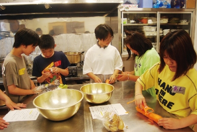 写真：夕食作りで野菜の皮をむく子どもたち
