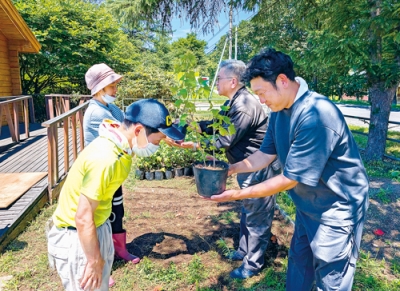 写真：利用者から苗を受け取る（右から）大塚代表取締役と中村常務