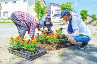 写真：植樹升に丁寧に花を植える会員たち