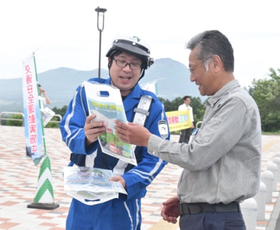 写真：ＳＡ利用者（右）に啓発物を手渡し、飲酒運転根絶などの意識高揚を図る参加者