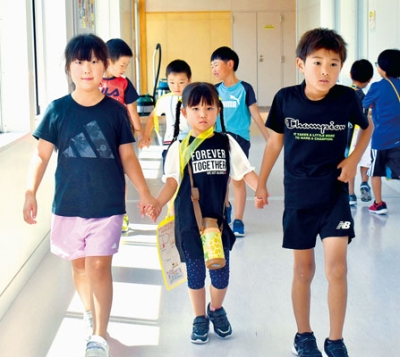 写真：園児（中央）と手をつなぎ、学校内を案内する伊達小２年生