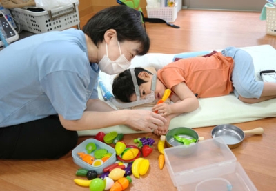 写真：東京都内の「障害児保育園ヘレン」の研修で、子どもを見守る看護師の村井有美さん＝６月