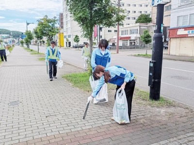 写真：歩道のごみを拾い集める富士建設の社員ら
