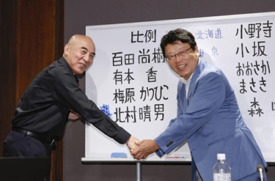 写真：比例代表で当選を決めた北村晴男氏（右）と握手する日本保守党の百田代表＝２０日午後９時１２分、東京都中央区