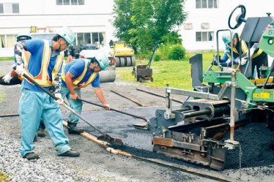 写真：アスファルトを流し通路を舗装する北紘建設社員ら