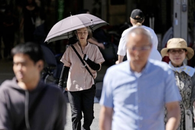 写真：強い日差しの中、日傘を差して歩く人たち＝２６日午前、大阪市北区