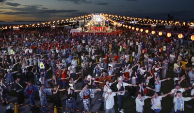 写真：大阪・関西万博で開かれたギネス世界記録に挑戦するイベントで、万博テーマソングに合わせて踊りを披露する人たち。同時に盆踊りをする参加者の人数と国籍数で記録達成となった＝２６日夕、大阪市此花区の夢洲