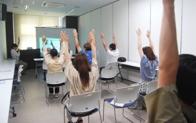 写真：座ったままできるストレッチを実践する参加者ら