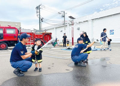 写真：消防士姿で放水体験をする子どもたち