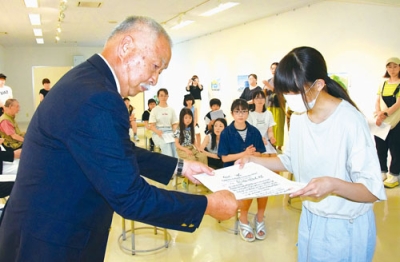 写真：最高賞・室蘭市民美術館をささえる会賞の賞状を受け取る伊藤さん（右）