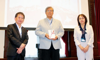 写真：目録を手にする常本理事長（中央）と戸川社長（左）（提供写真）