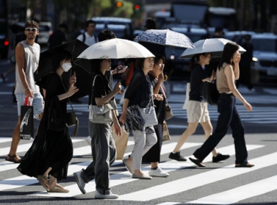写真：日傘を差して歩く人たち＝２９日午後、東京・有楽町