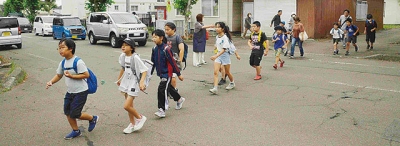 写真：渋滞する道路を横断する子どもたち＝３０日午前１０時、登別市千歳町