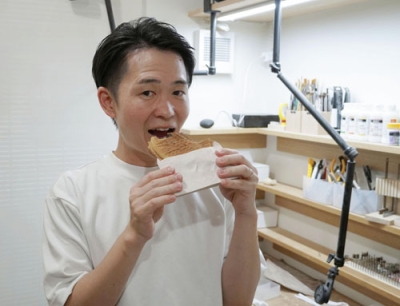 写真：木彫りの鯛焼きを持つキボリノコンノさん＝７月、浜松市