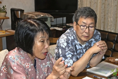 写真：宿泊客に町の案内をする船橋勇逸さん（右）と妻喜美子さん＝７月、小樽市