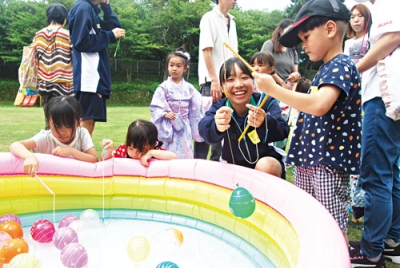 写真：高校生ボランティアとヨーヨー釣りを楽しむ園児