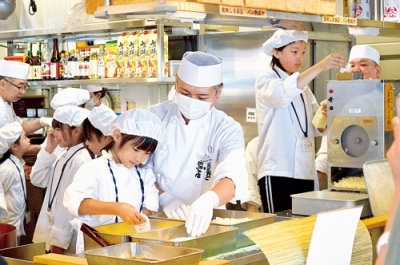 写真：店員に教わりながら衣付けの作業をする子ども