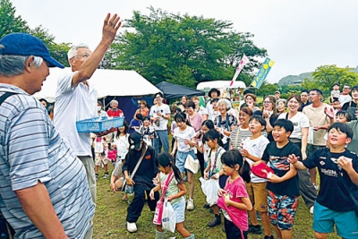 写真：「こっちにも投げて」餅まきに笑顔の地域住民たち
