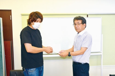 写真：善意を手渡した山本代表（左）