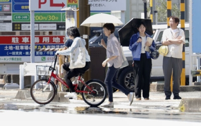 写真：「逃げ水」が見られた静岡市駿河区を歩く人たち。気温４１・４度を観測した＝６日午後