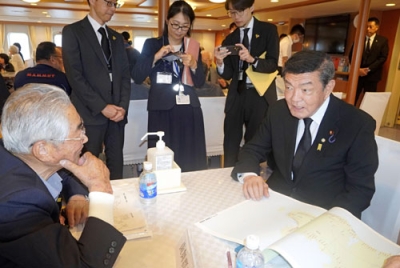 写真：「洋上慰霊」の船内で、北方領土の元島民と交流する伊東沖縄北方相（右）＝７日午前、根室市の根室港沖
