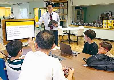 写真：佐渡さんからプログラミングの基礎を学ぶ児童ら（提供写真）