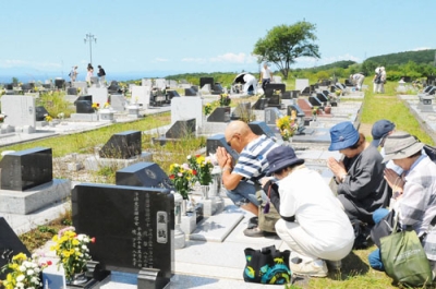 写真：故人の墓前に手を合わせる望洋台霊園の墓参客