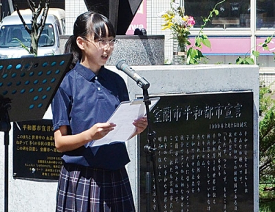 写真：父が制作したオブジェ「いのりのかたち」の前でメッセージを代読する翠さん