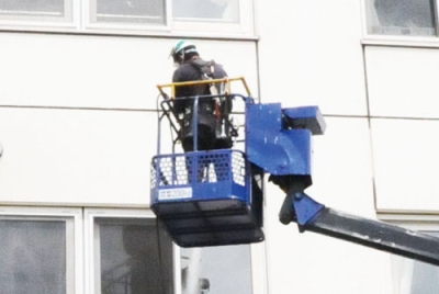 写真：高所作業車を使い、教室の窓をきれいにする江尻建設の社員