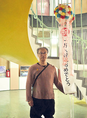 写真：１万人目となった稲垣さんに記念のくす玉が割られた