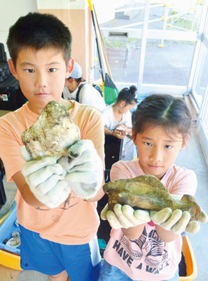 写真：発掘した土器やシカの骨などを手にする子どもたち