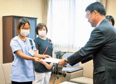 写真：新井病院事業管理者から辞令を受け取るトゥエ・トゥエ・ウーさん（左）