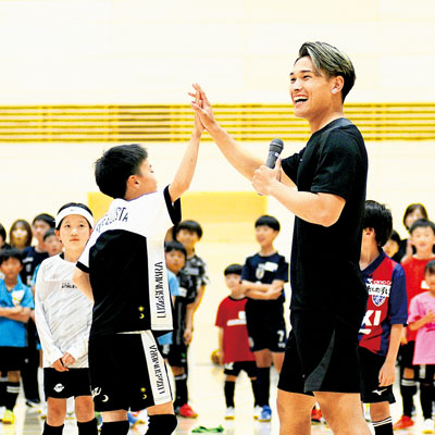 写真：子どもと笑顔でハイタッチする松木選手