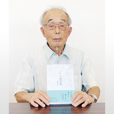 写真：自費出版した詩集「人間賛歌」を持つ須藤さん