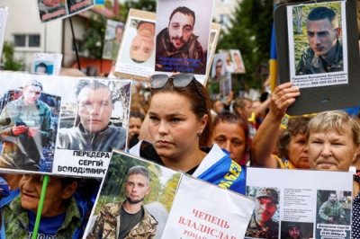 写真：ロシアの捕虜になっている親族の写真を持つ人々。行方が分かることを望んでいる＝２４日、ウクライナ（ロイター＝共同）