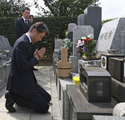 写真：相嶋静夫さんの墓前で謝罪する警視庁の鎌田徹郎副総監。奥の２人は相嶋さんの息子＝２５日午前、横浜市の霊園（代表撮影、画像の一部を加工しています）