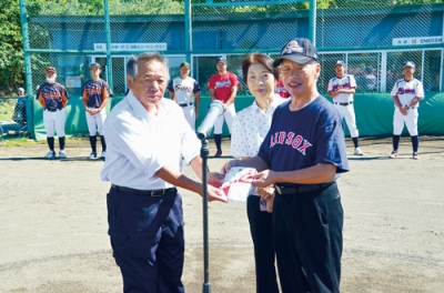 写真：寄付金を渡す山本代表取締役（右）