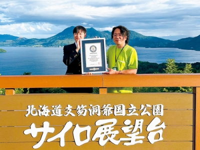写真：洞爺湖をバックにギネス記録成功を喜ぶ渡部代表取締役社長（右）（提供写真）