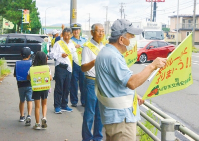 写真：黄色い旗を手に安全運転を呼びかける啓発参加者ら