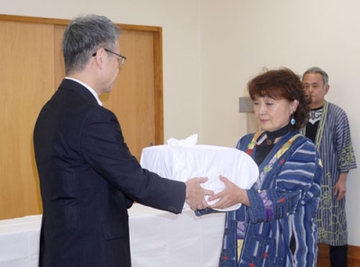 写真：遺骨を受け取る釧路アイヌ協会の桃井芳子会長（右）＝３０日午前、釧路市
